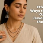 woman wearing oxidised silver jhumka earrings, layered necklace, and a statement ring, styled with an off-white khadi V-neck blouse in a modern boho office setting. 5 Effortless Ways to Wear Oxidised Jewellery to the Office