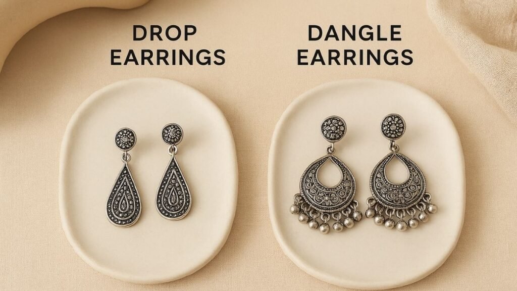 Side-by-side comparison of oxidised silver drop earrings and dangle earrings displayed on ceramic plates with a beige fabric background, clearly showing the difference in design and movement. What Are The Differences Between Drop Earrings And Dangle Earrings