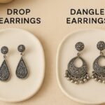 Side-by-side comparison of oxidised silver drop earrings and dangle earrings displayed on ceramic plates with a beige fabric background, clearly showing the difference in design and movement. What Are The Differences Between Drop Earrings And Dangle Earrings