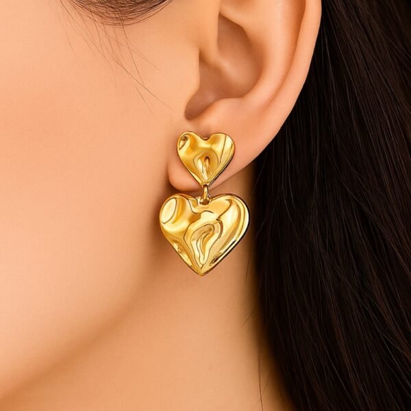 Gold Double Heart Anti Tarnish Earrings worn on model ear – 18K gold plated hammered drop design, waterproof stainless steel, lightweight, hypoallergenic, with push plug closure – Avvni The Store