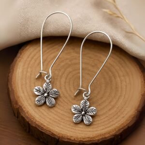 Avvni Flower Motif Oxidised Earrings by Avvni Jewellery, A pair of silver flower dangle earrings with long hooks displayed on beige aesthetic boho wood plate background.