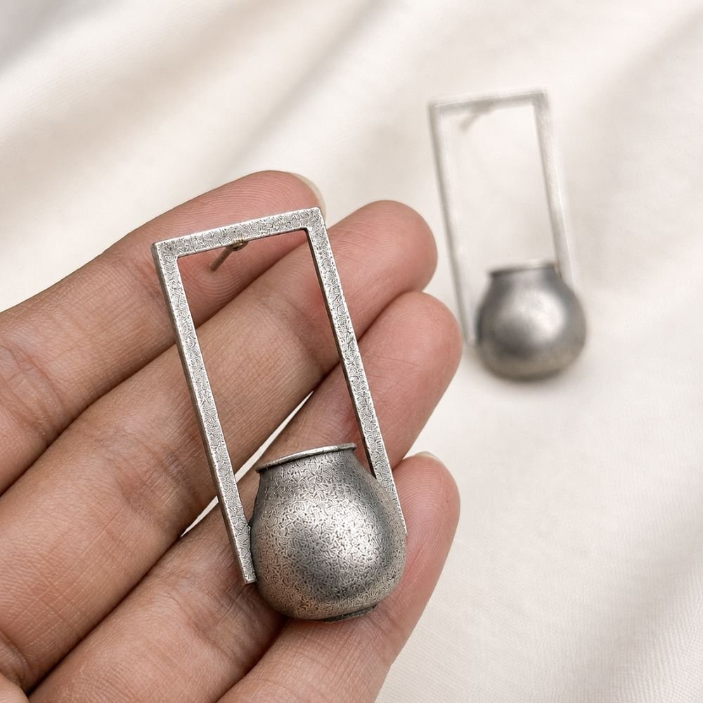 Avvni Oxidised Silver Tribal Pot Drop Earrings | Avvni The Store Handheld view of detailed Oxidised Silver Tribal Pot Drop Earrings