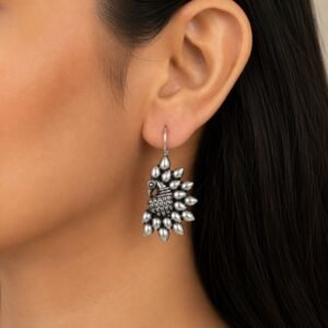 Avvni Oxidised Silver Peacock Drop Earrings with intricate peacock design worn on model ear
