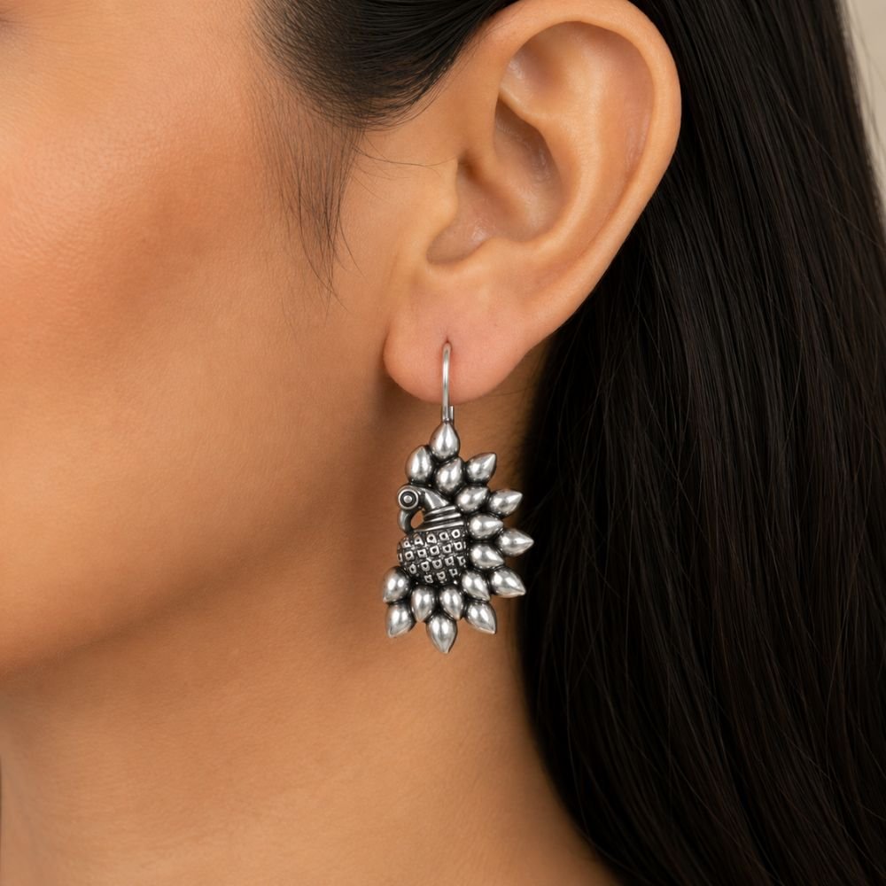 Avvni Oxidised Silver Peacock Drop Earrings | Avvni The Store Avvni Oxidised Silver Peacock Drop Earrings with intricate peacock design worn on model ear